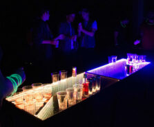 Glow LED Beer Pong Table with people playing it at a party after renting the table. The LED Beer Pong table is lit orange and purple. 